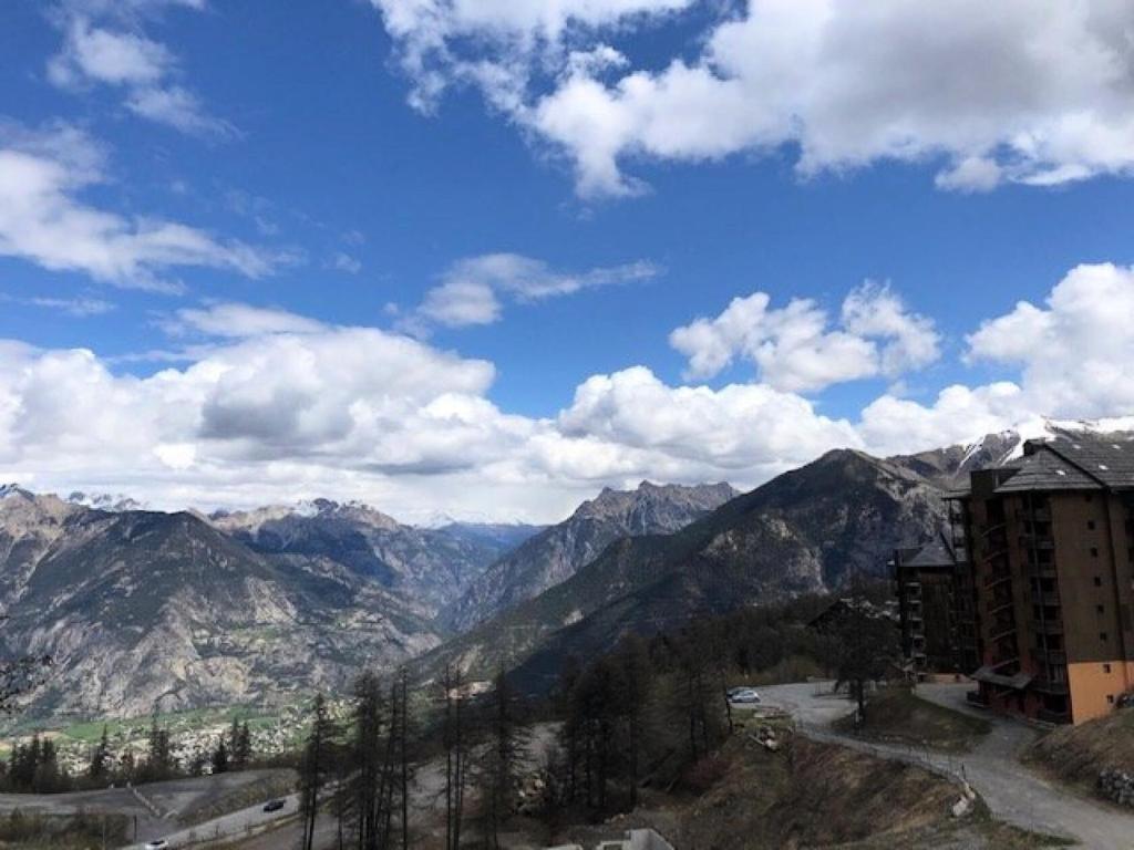 - une vue sur une chaîne de montagnes avec un bâtiment dans l'établissement Résidence Antares - Beau T4 à Risoul 50m des pistes dans résidence avec piscine et spa MAE-6991, à Risoul