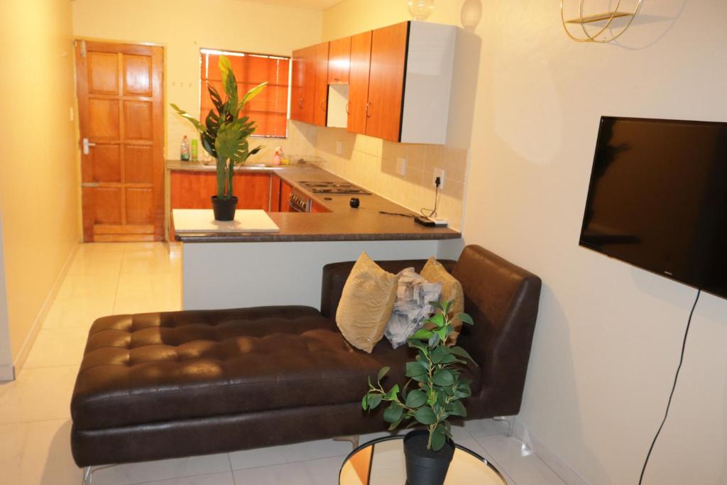 a living room with a leather couch and a kitchen at Sleep in Crestwave villas in eMalahleni