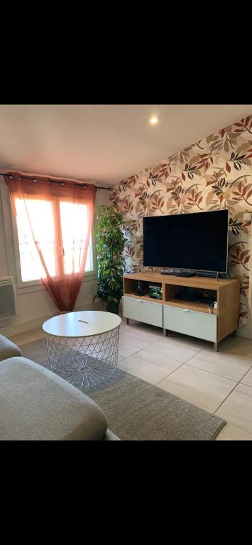 un salon avec une télévision à écran plat et une table dans l'établissement Le Terra, à Brignoles