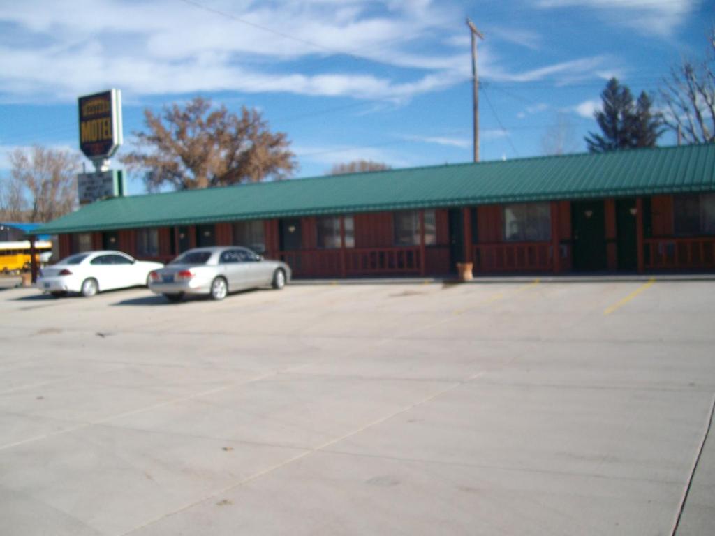 a building with two cars parked in a parking lot at Western Motel Ranchester in Ranchester