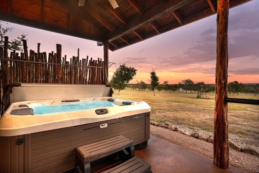 ein Whirlpool auf einer Veranda mit Blick auf ein Feld in der Unterkunft Rockin' R - Shooting Star Cabin in Fredericksburg