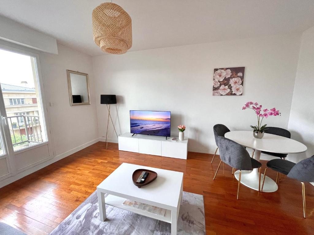 un salon avec une table et une télévision dans l'établissement Centre ville Troyes - Le Voltaire, à Troyes