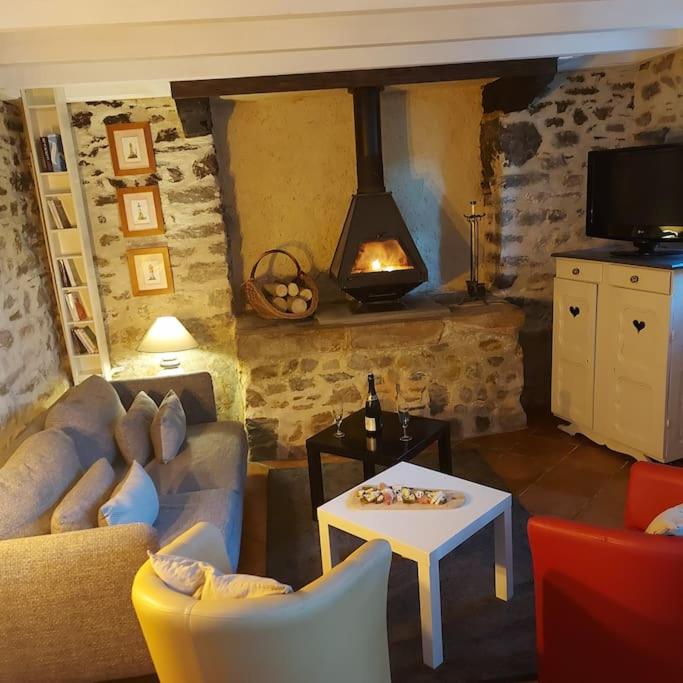 - un salon avec un canapé et une table avec une cheminée dans l'établissement Penty typique Kercab dans un ancien moulin, à Plomodiern