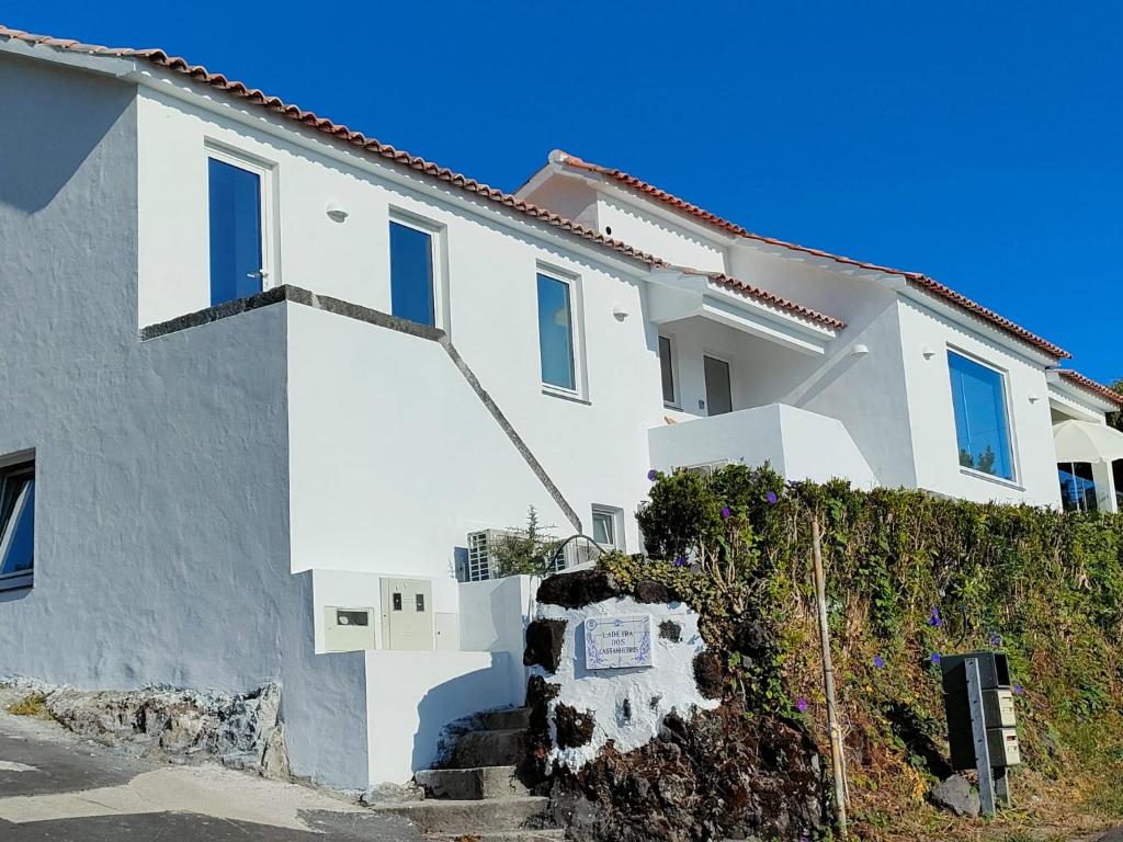 une maison blanche avec un panneau devant dans l'établissement Casa dos Castanheiros - The White Cottage, à Canto da Areia
