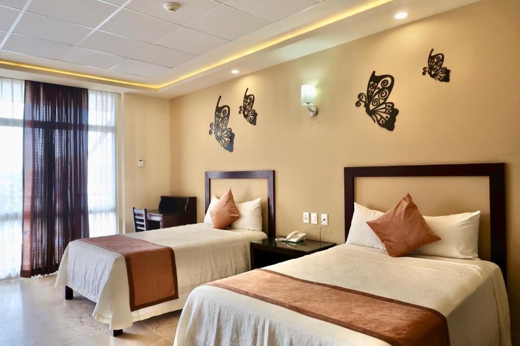 una camera d'albergo con due letti e farfalle sul muro di Hotel Yorio Inn a Tuxpan de Rodríguez Cano