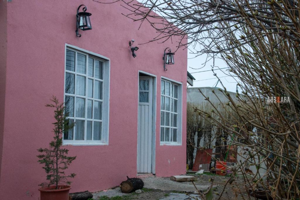 a pink house with a white door and windows at Hospedaje PIEDRA BUENA in Comandante Luis Piedra Buena