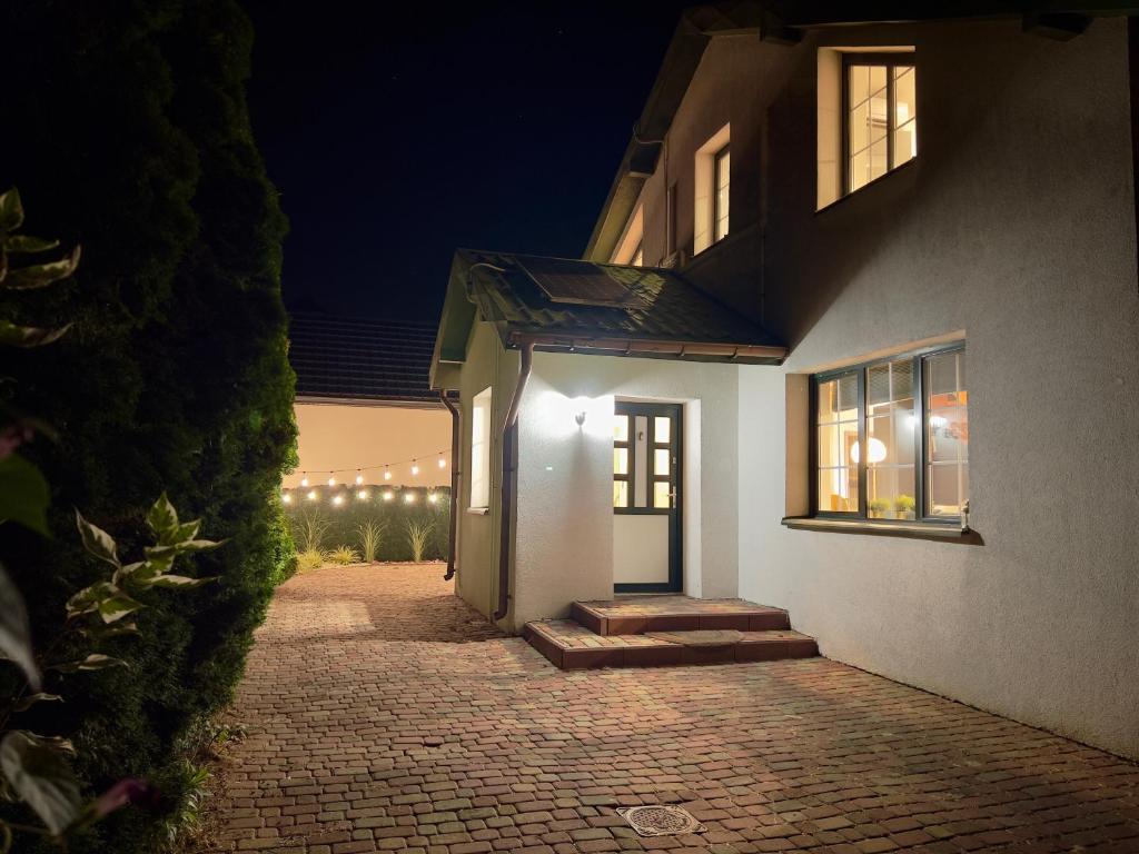 a white house at night with a brick driveway at Duży domek na Polnej in Konin