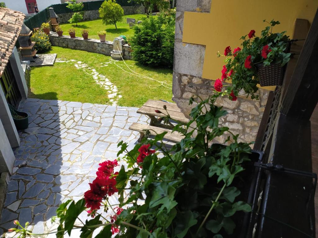 a garden with red flowers and a wooden bench at Gran Pedroso de Llanes in Llanes