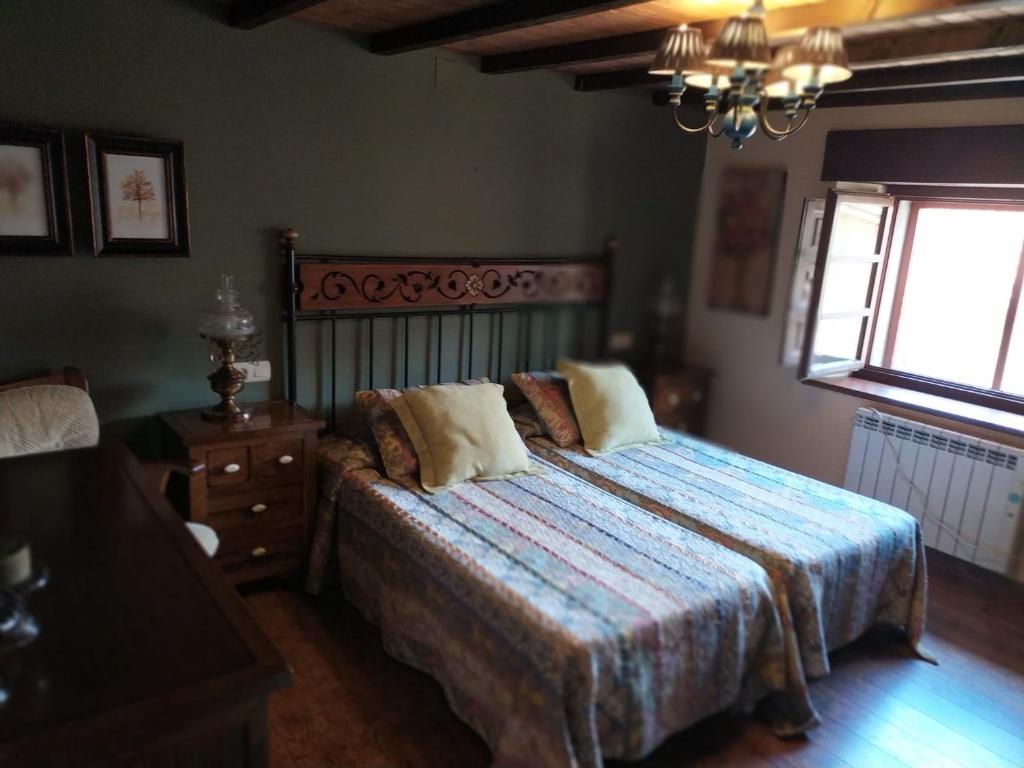 a bedroom with a bed and a window and a chandelier at Gran Pedroso de Llanes in Llanes