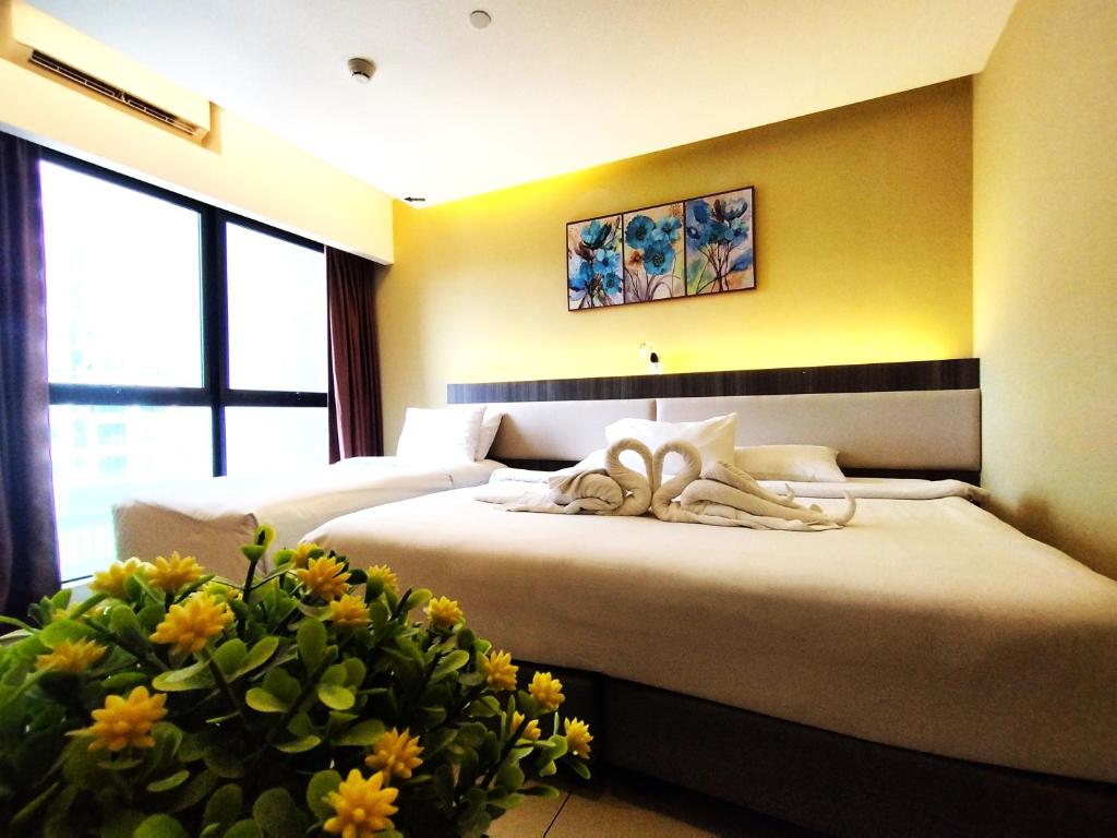 two beds in a hotel room with flowers in a room at Genting GetawayStayCationHut AT Ion Delemen in Genting Highlands