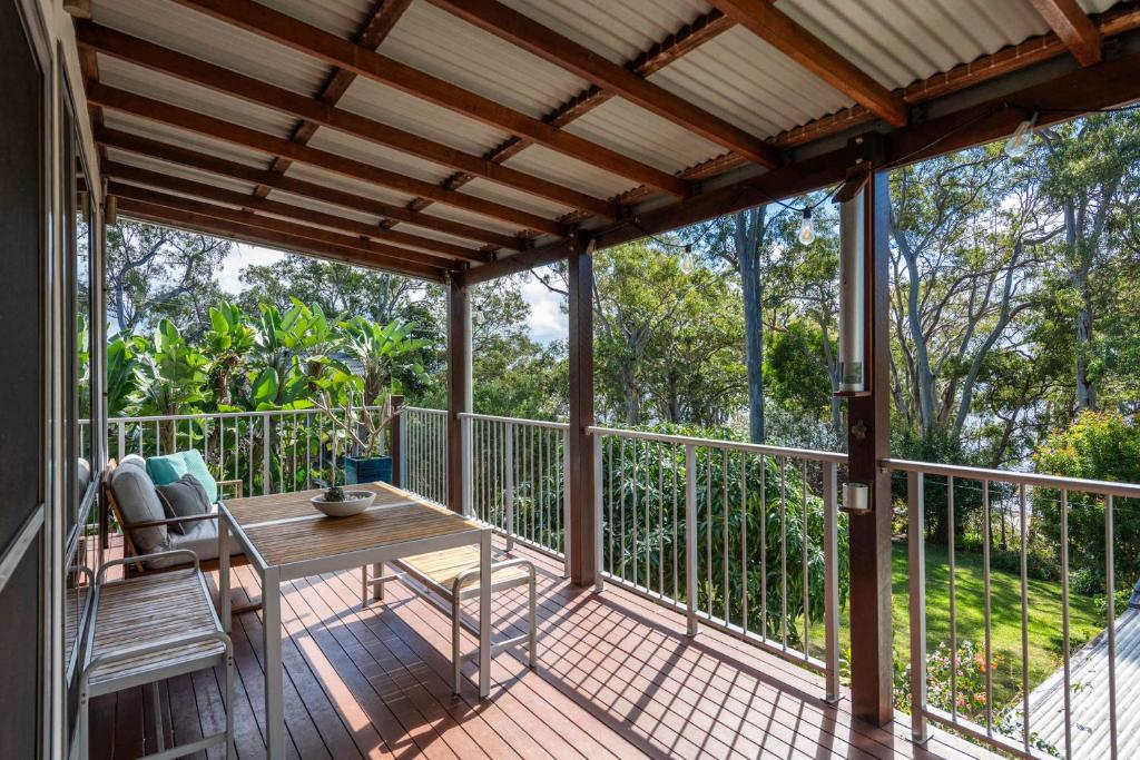 eine Veranda mit einem Tisch und Stühlen auf einer Terrasse in der Unterkunft Casa Del Lago - Oceanstays - Lakehouse in Yamba