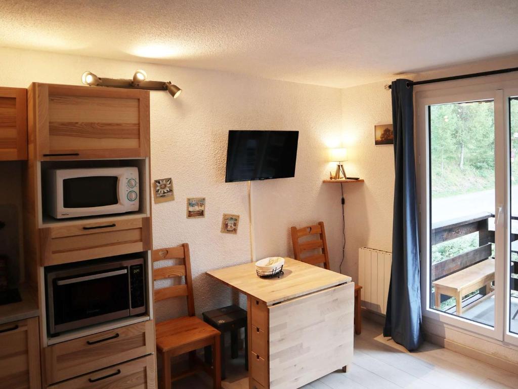 Cette chambre comprend une cuisine équipée d'un four micro-ondes et d'une table. dans l'établissement Studio cosy pour 6 à 5 min des pistes - FR-1-322-642, aux Orres