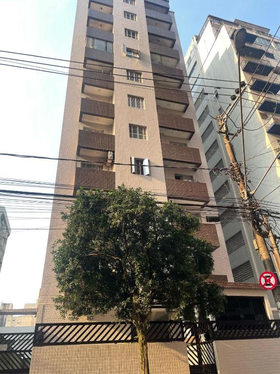 a tall building with a tree in front of it at Sala living 809 in São Vicente