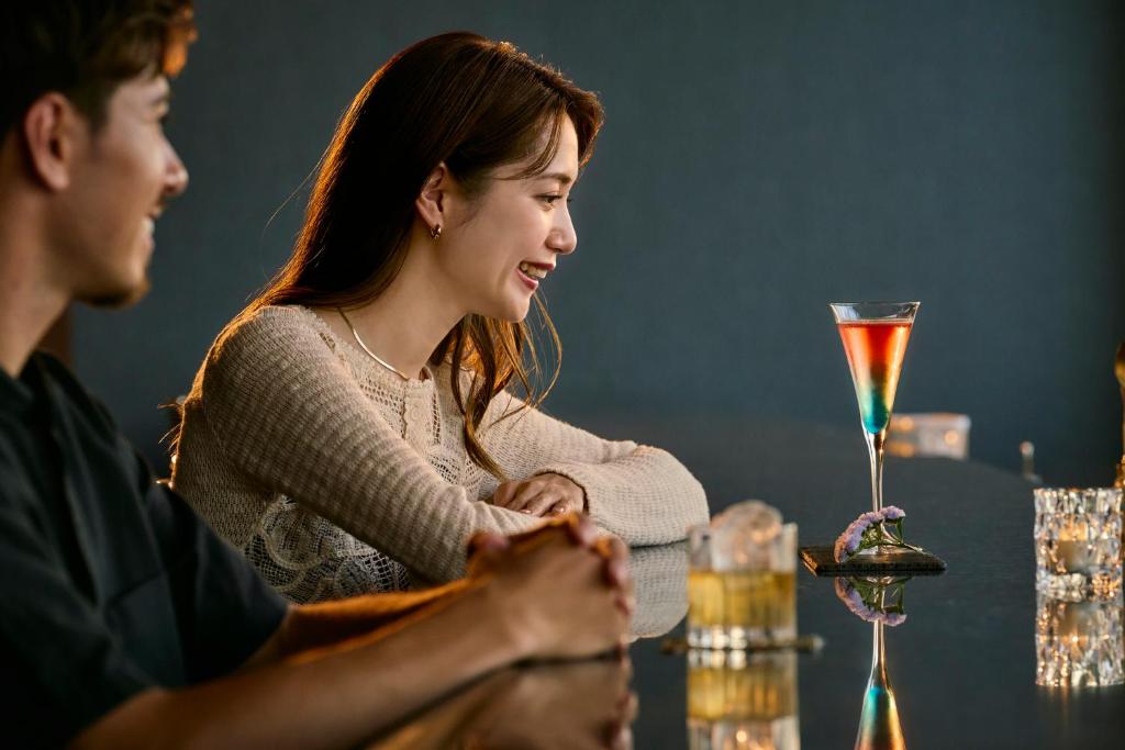 a man and a woman sitting at a table with a drink at Lake Biwa Otsu Prince Hotel in Otsu