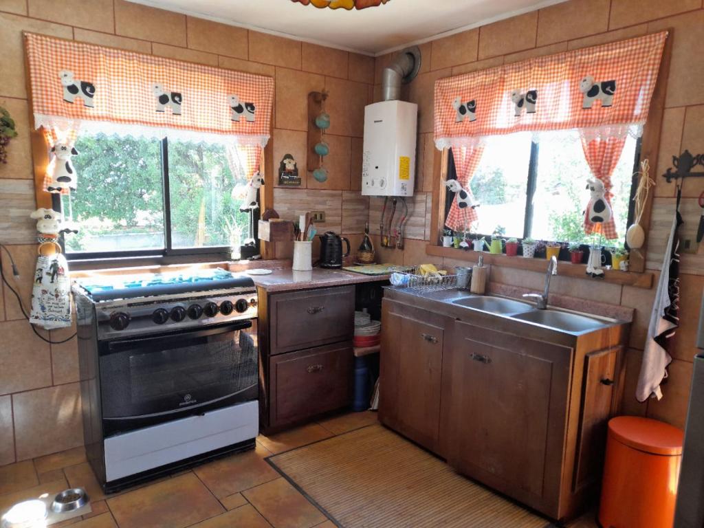 a kitchen with a stove and a sink and two windows at Casa Lago Ranco in Lago Ranco