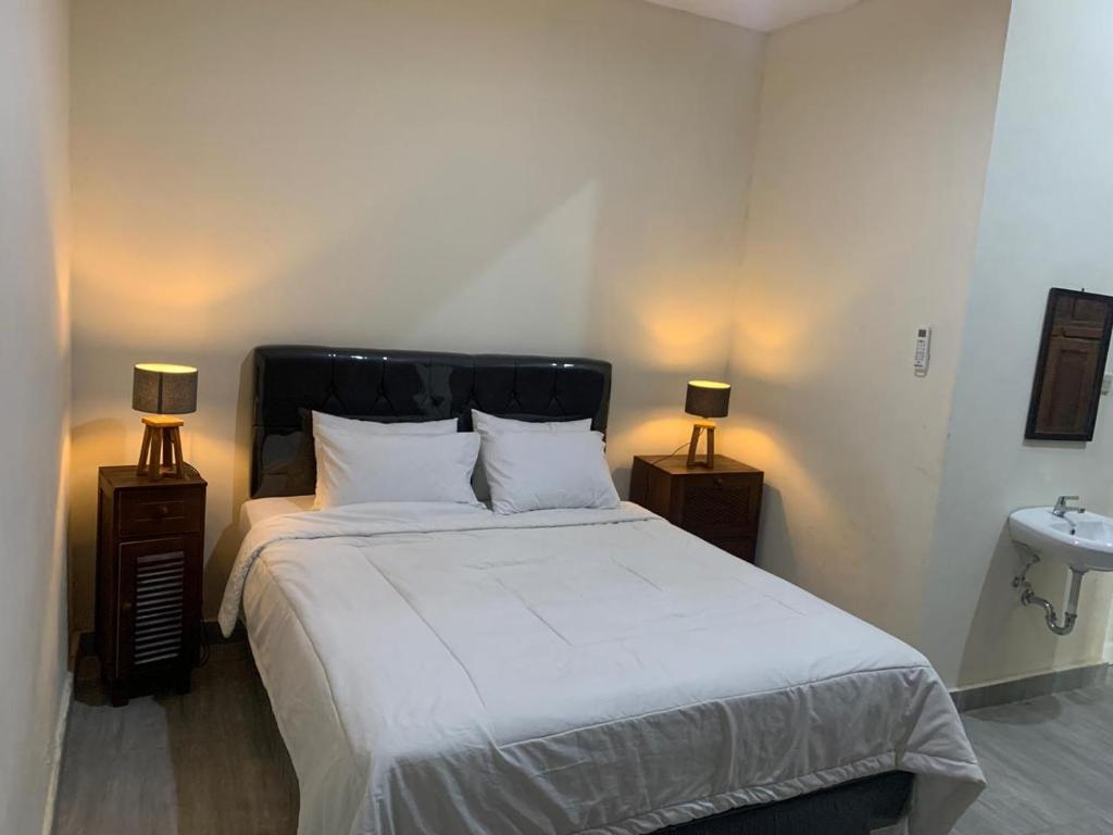 a bedroom with a large bed with two lamps at Omah Pinter in Beran-kidul