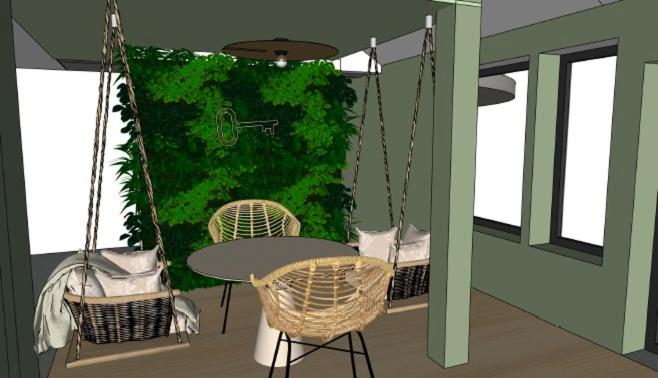 een balkon met een tafel en stoelen en een groene muur bij Les Doms d'Alfred - GRINDOM in Plombières