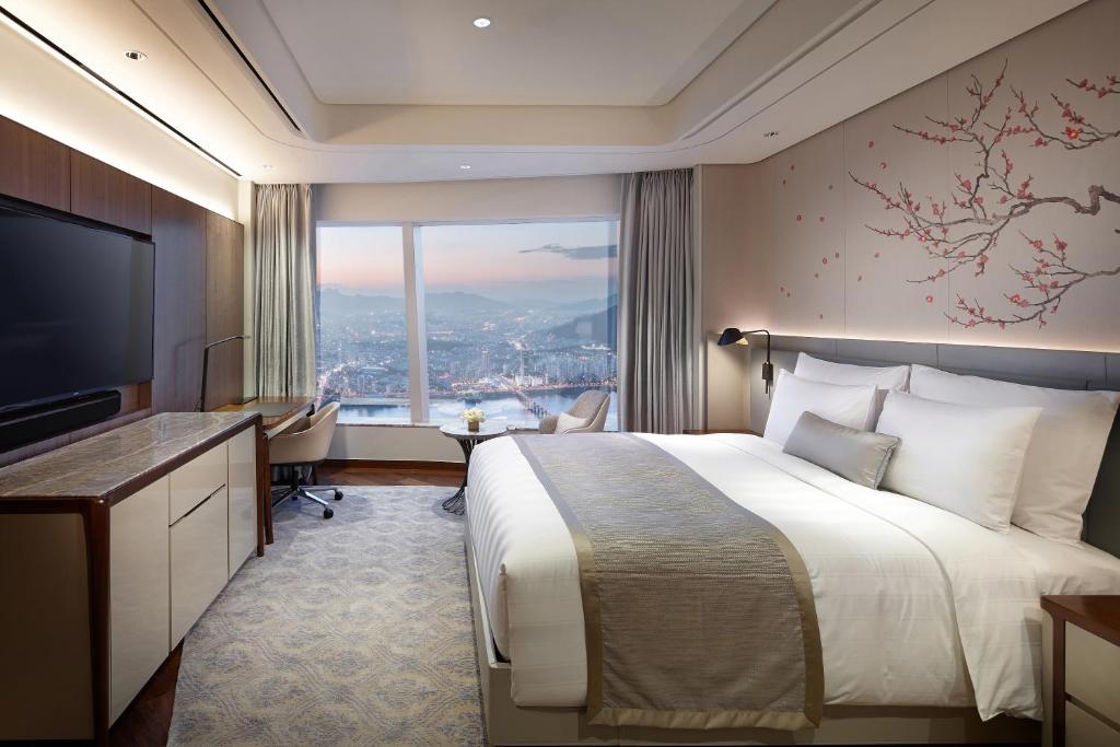 a hotel room with a bed and a large window at Signiel Seoul in Seoul