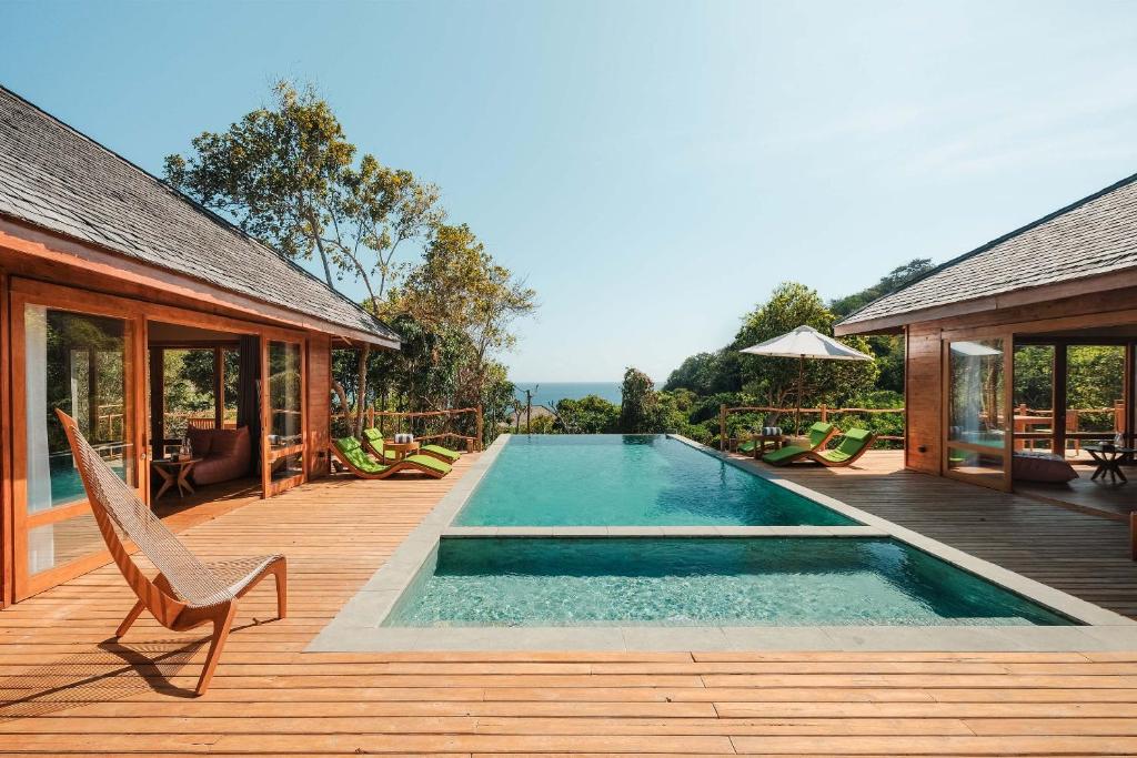 una piscina su una terrazza in legno accanto a una casa di TUNAK Resort Lombok a Bumbang