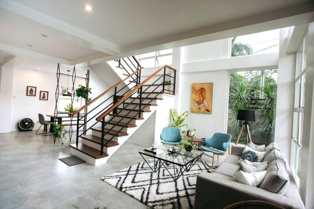 a living room with a staircase and blue chairs at Casa Bianca Dumaguete in Bolocboloc