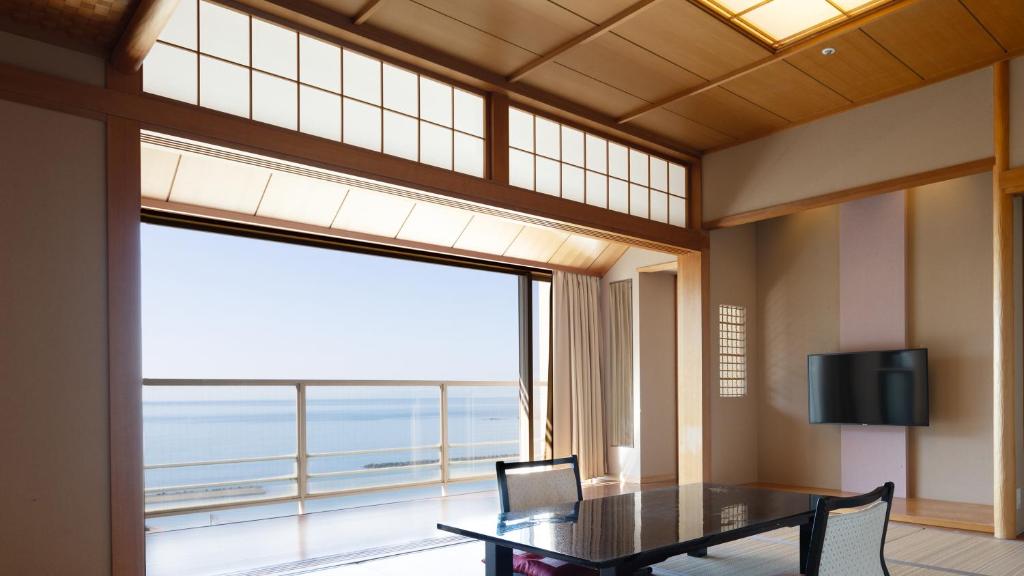 西伊豆町Nishiizu Crystal View Hotel的一间带桌子和大窗户的用餐室