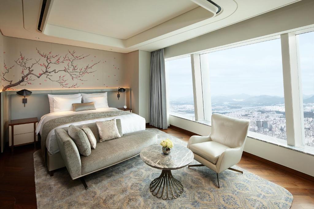 a bedroom with a bed and a couch and a chair at Signiel Seoul in Seoul