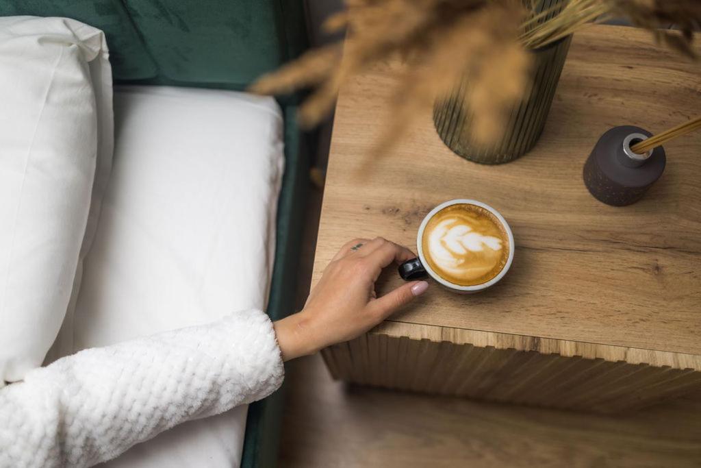 eine Person, die eine Tasse Kaffee auf einem Tisch hält in der Unterkunft Miško terapija po egle in Kriviliai