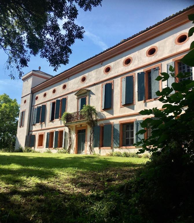 un grand bâtiment avec des fenêtres sur une pelouse dans l'établissement Charmant appartement en rdc dans château avec parc, à Villefranche-de-Lauragais