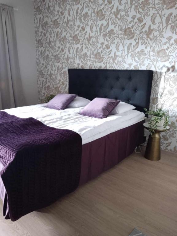 a bed with a purple blanket and pillows on it at Ahtinhovi in Ylivieska