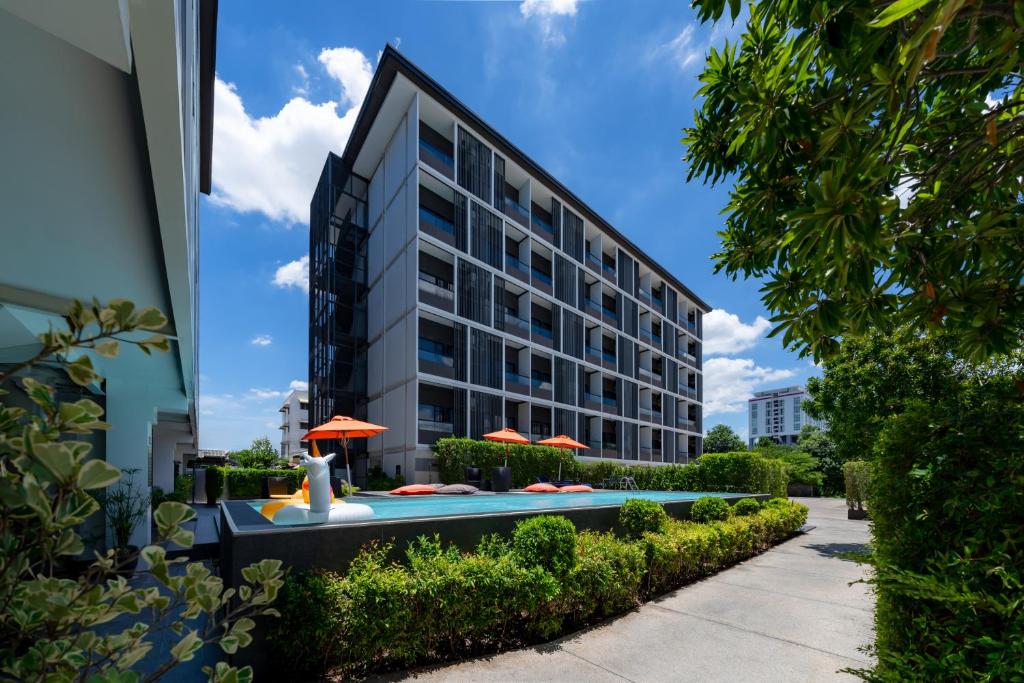 A compact outdoor pool sits beside the hotel buildings and landscaped pathways.