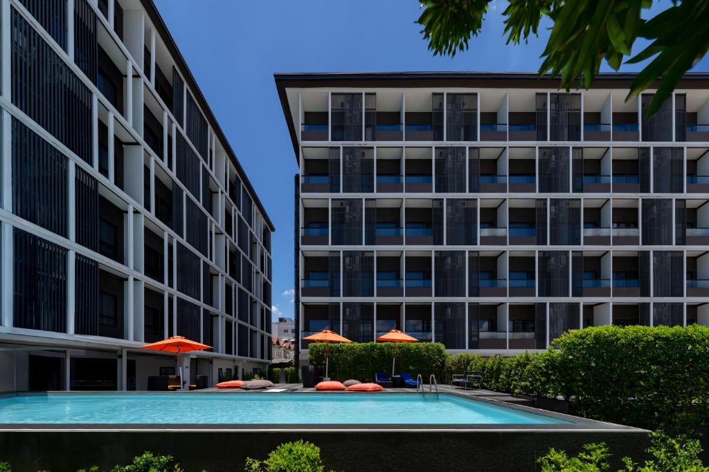 The pool is framed between two hotel buildings with umbrellas along the far deck.