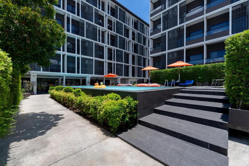 Black steps lead through a landscaped courtyard toward the raised pool deck.