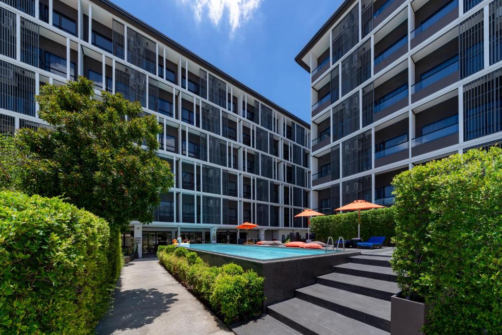 Steps rise beside a small courtyard pool surrounded by hotel buildings and greenery.