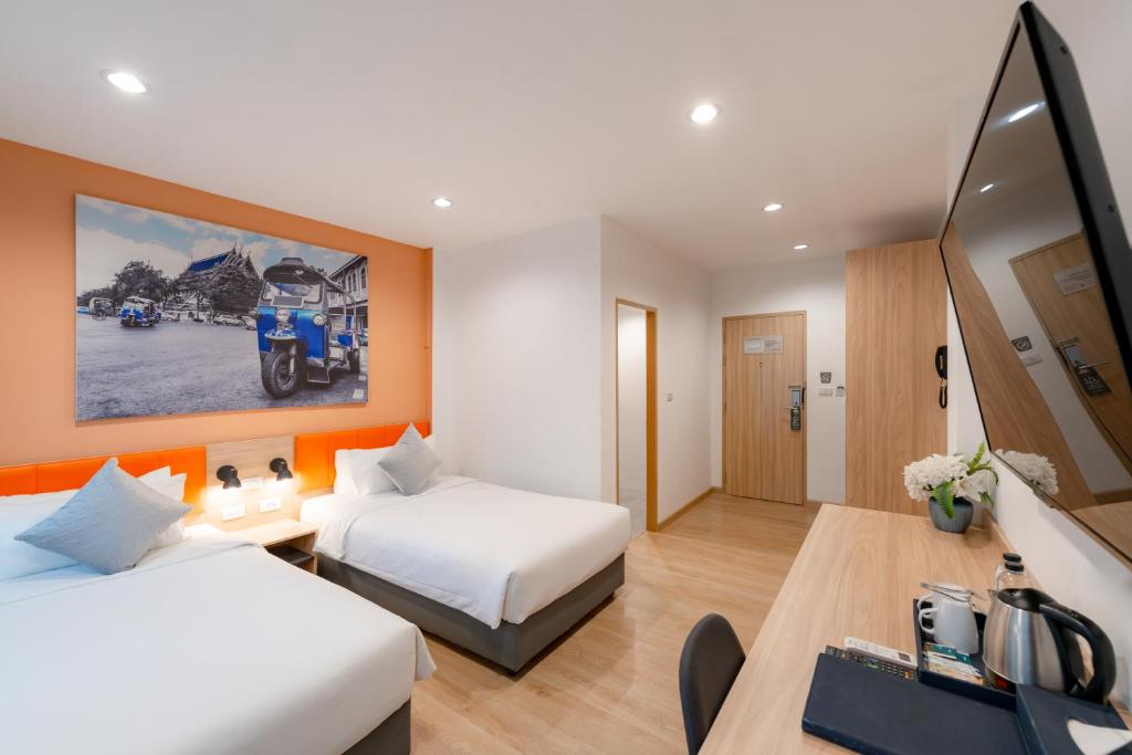 A twin room with two beds, a long desk, tea station and large wall-mounted television.