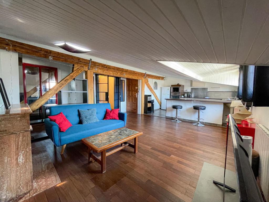 un salon avec un canapé bleu et une table dans l'établissement La Cachette - Logement Atypique Sous Les Toits, à Toulouse