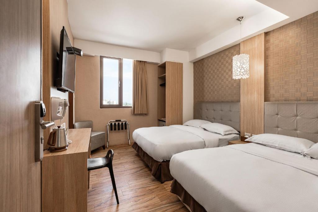 una camera d'albergo con due letti e una televisione di The Riverside Hotel Hengchun a Città Vecchia di Hengchun
