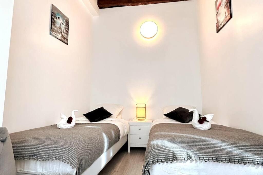 deux lits dans une chambre aux murs blancs dans l'établissement Parc Luxembourg, à Paris