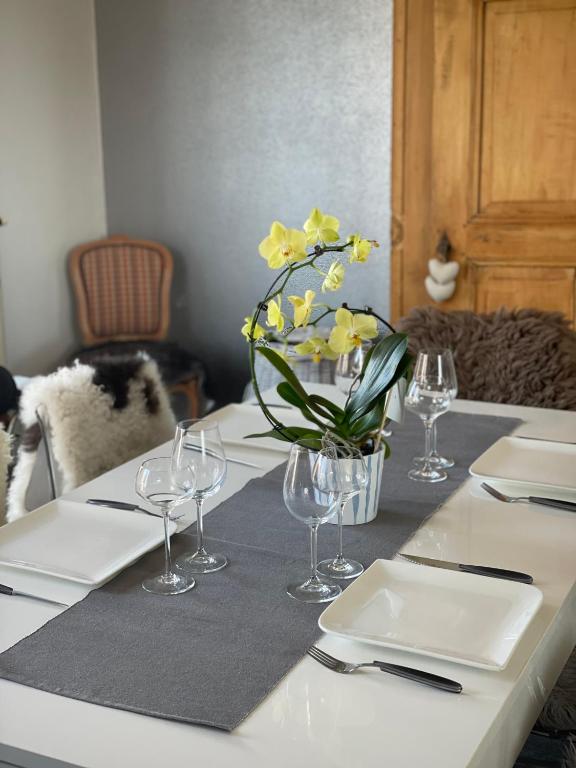 une table avec des assiettes, des verres et un vase de fleurs dans l'établissement Du côté des vignes en Alsace, à Turckheim
