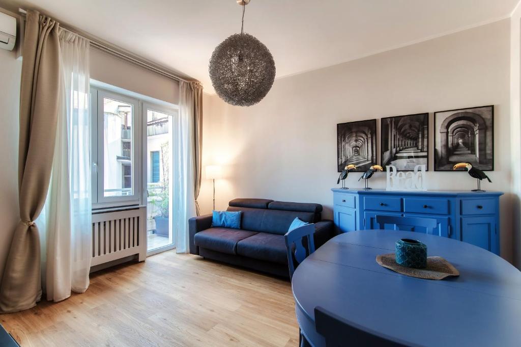 Una sala de estar con un sofá azul y una mesa. en Turchese - by MyHomeInComo, en Como