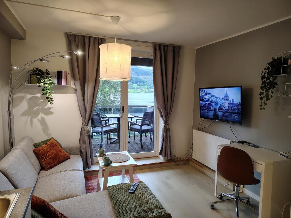 a living room with a couch and a tv at Oppheim Holiday Apartment in Øyjordi