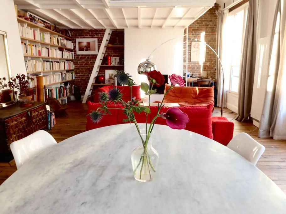 a vase with flowers on a table in a living room at Loft style condo 4 people in central and trendy Paris in Paris