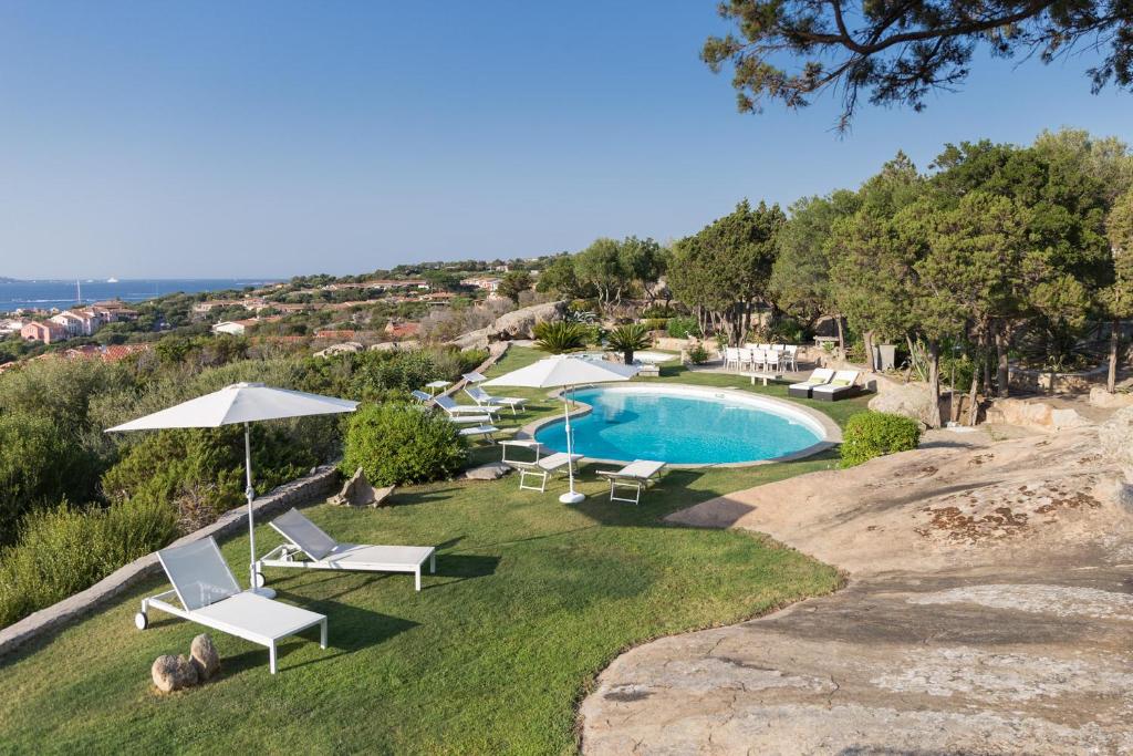 a pool with chairs and umbrellas in a yard at Suite Nuragus in Porto Rotondo