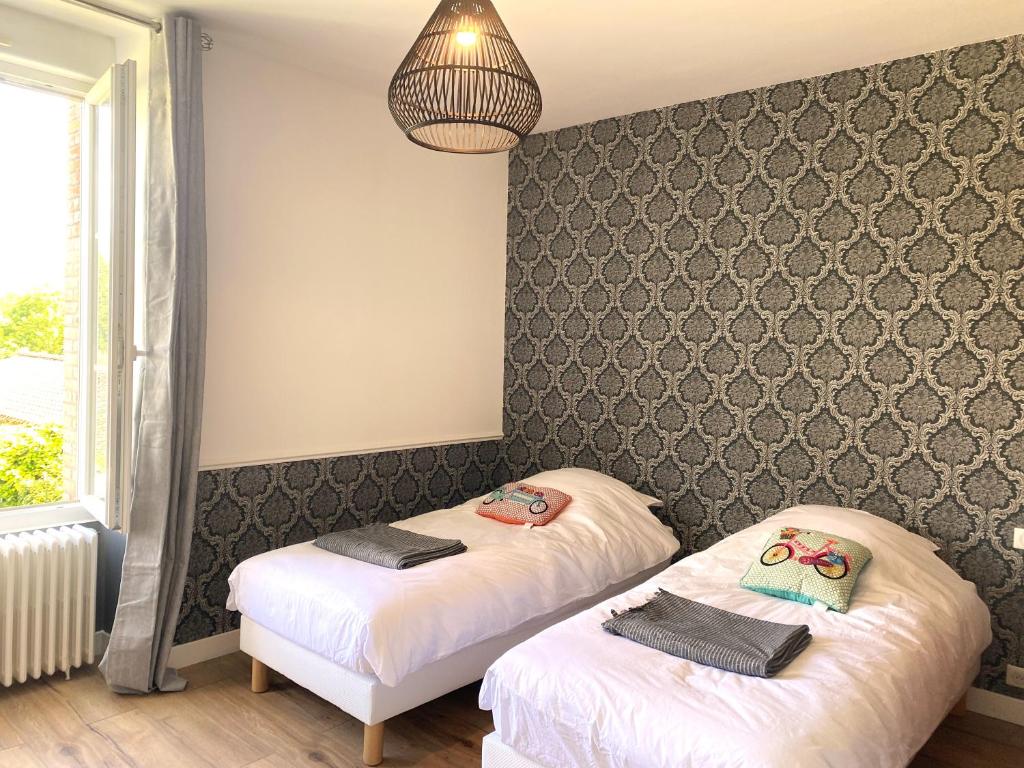 two beds in a room with a wall at CH1- MANOIR DU MOULINIER - Campagne - Calme - Petit-déj inclus - Table d'hôte sur réservation - Parking gratuit in La Limouzinière