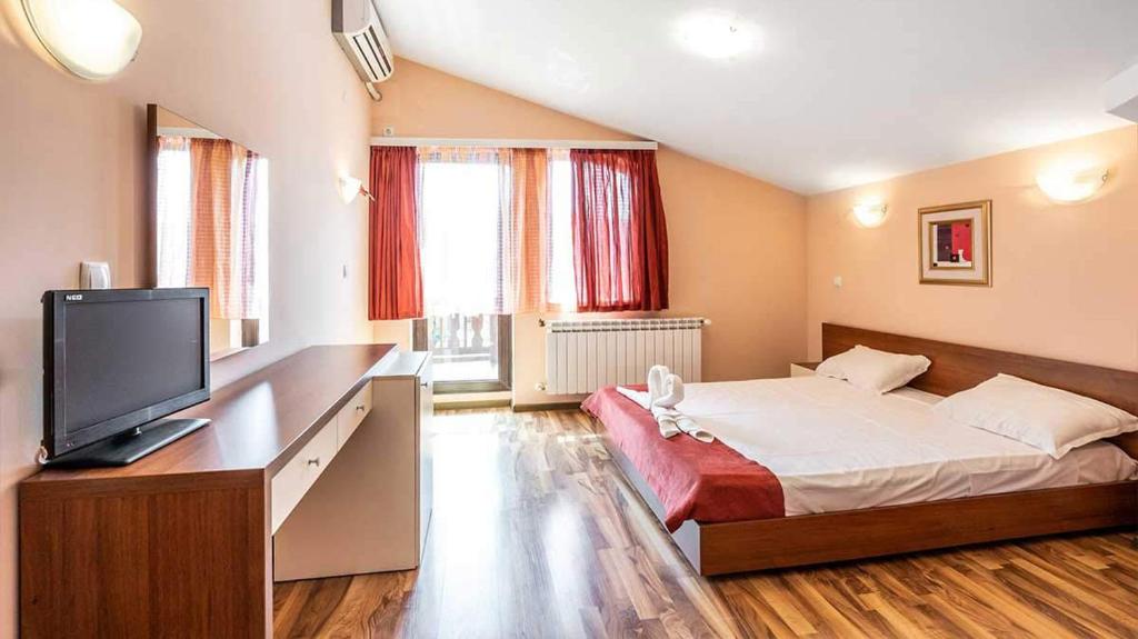 a bedroom with a large bed and a television at Хотел "Русенски лом" in Koshov
