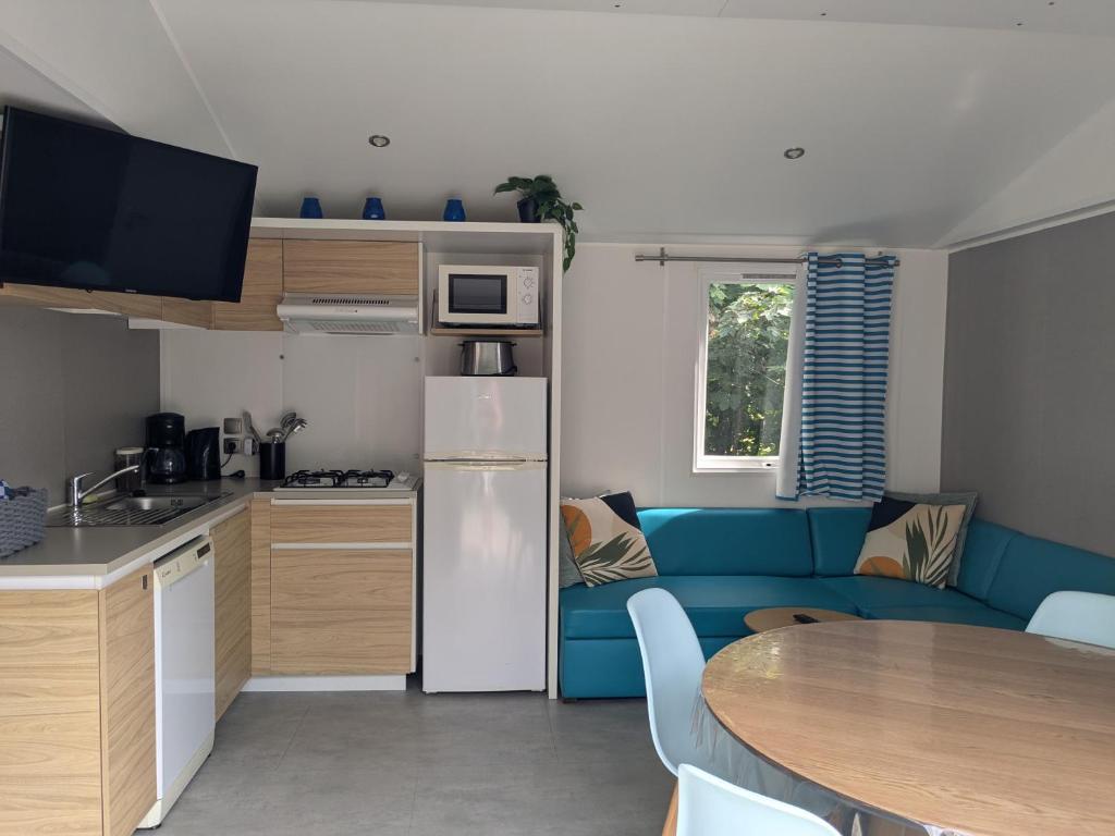 a kitchen and a living room with a blue couch at Cozy Tiny SolHouse 7 - Near Groningen - 5 Star Location in Kropswolde