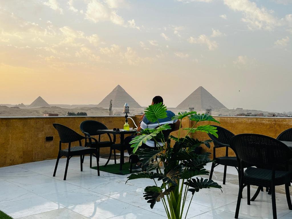 a person sitting at a table looking at the pyramids at golden mask pyramids view in Cairo