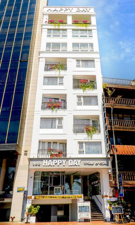 a white building with flower boxes on the windows at Happy Day Riverside Hotel & Spa Danang by Haviland in Danang