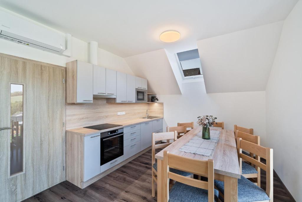 a kitchen with a table and chairs and a kitchen with white cabinets at Apartmány Jakub in Příseka