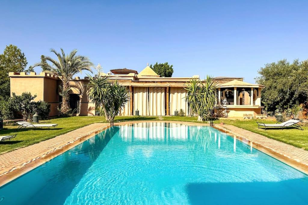 a large swimming pool in front of a house at DAR SMAWAR top piscine chauffée 15mn centre ville in El Caïd Omar
