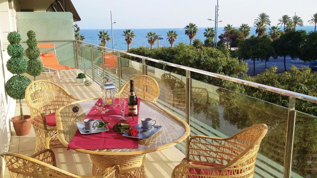 una mesa y sillas en un balcón con vistas al océano en ALEXANDRA´s BEACH-PORT, en Badalona